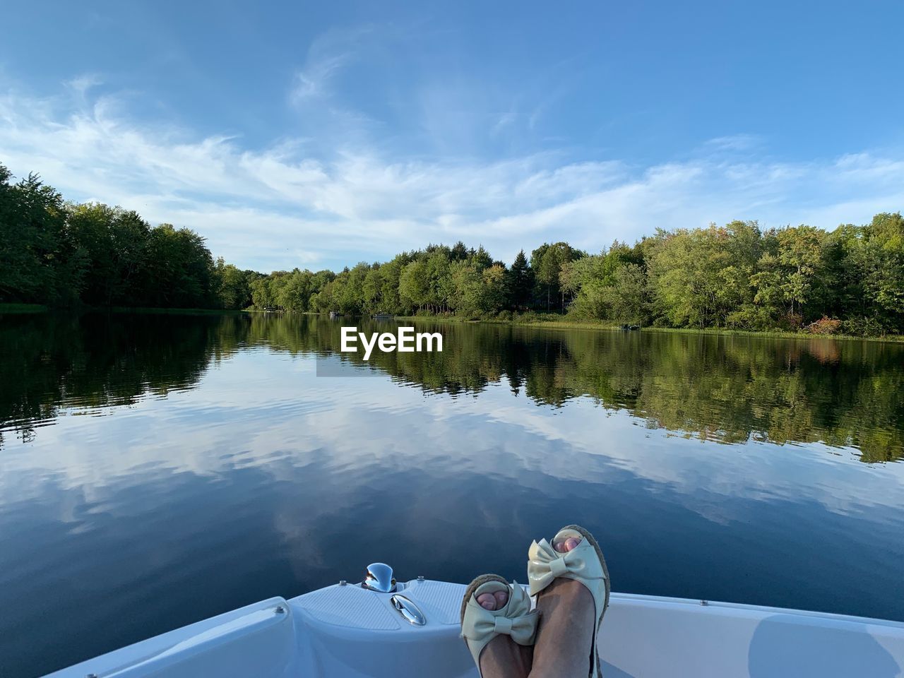 LOW SECTION OF PERSON ON LAKE AGAINST SKY