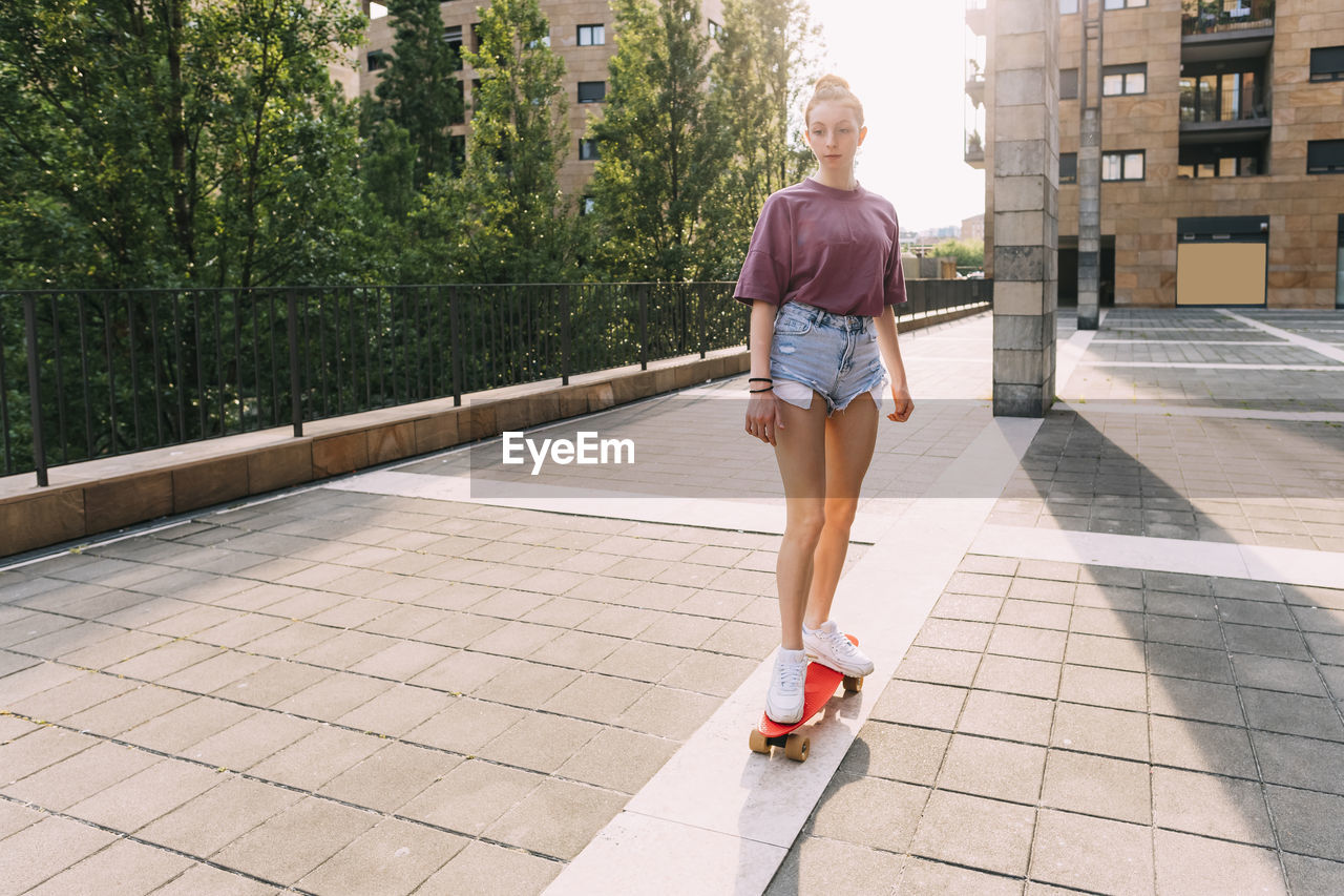 Teenage girl skateboarding on sunny day