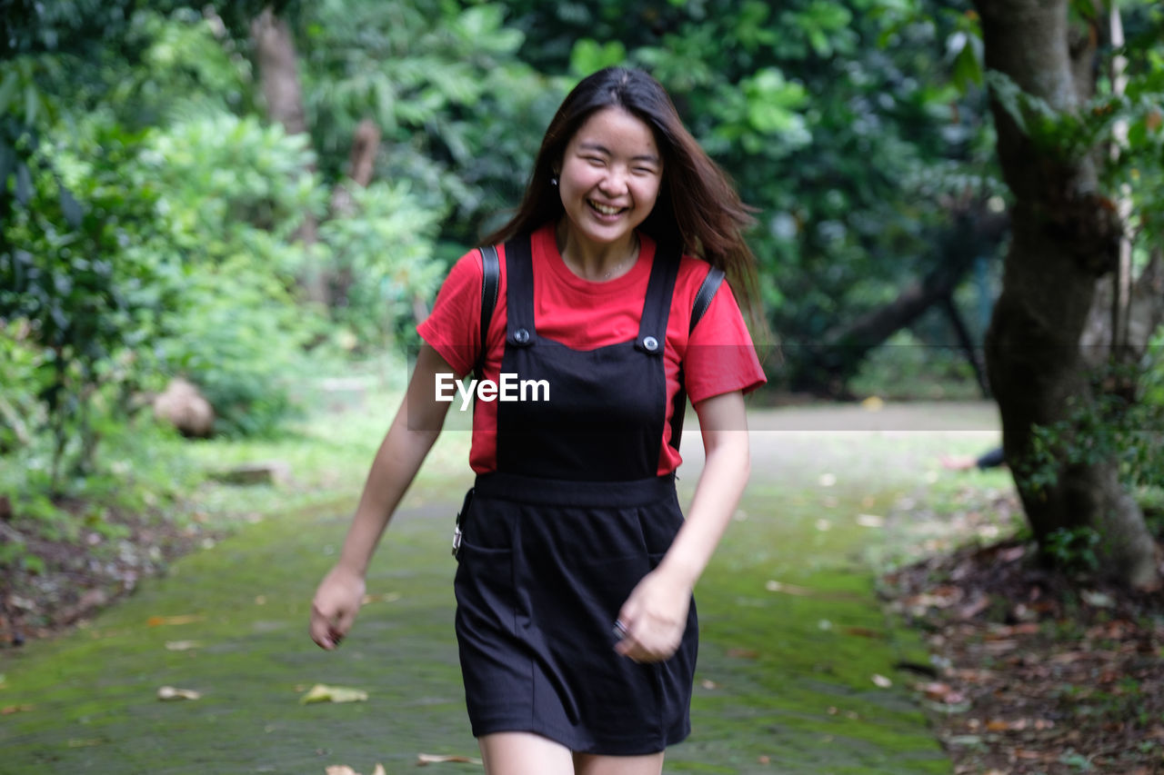 Portrait of beautiful young woman walking on footpath at park