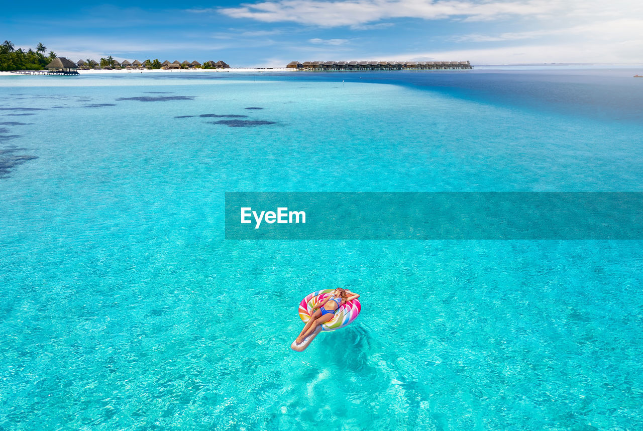 High angle view of woman lying on inflatable raft in sea during summer