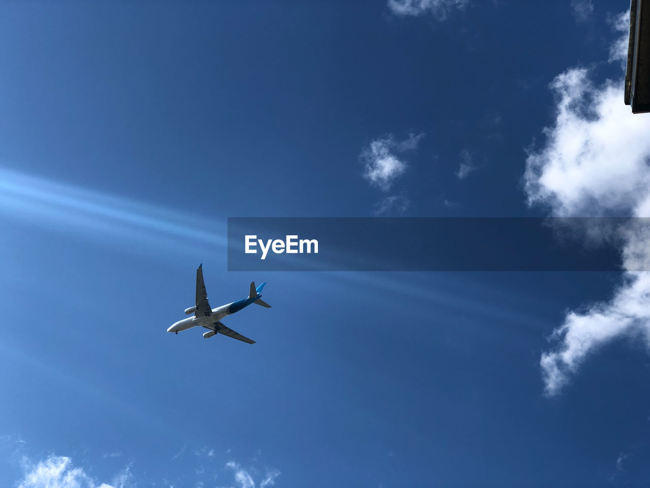 LOW ANGLE VIEW OF AIRPLANE IN FLIGHT AGAINST BLUE SKY