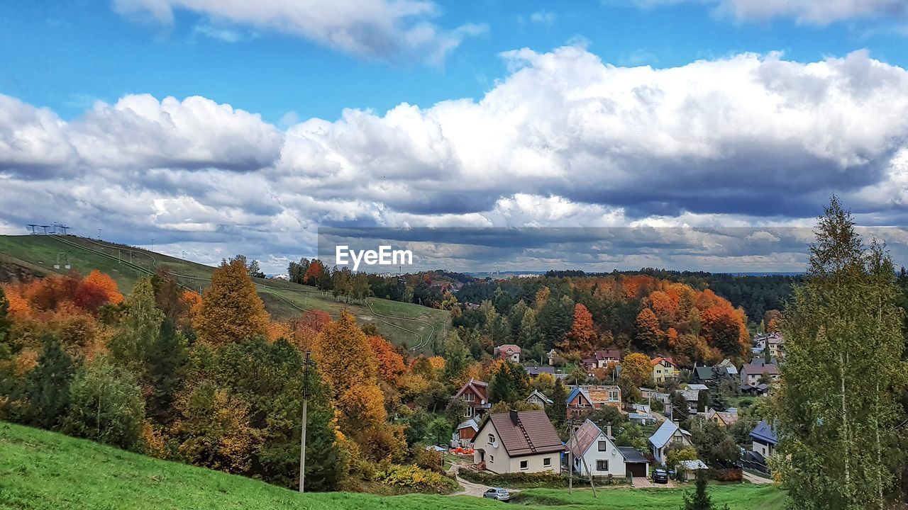 PANORAMIC SHOT OF TREES AND HOUSES AGAINST SKY