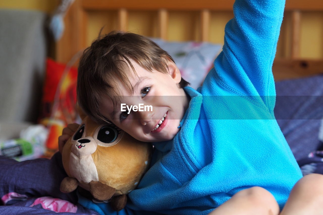 Portrait of cute boy lying down on bed at home