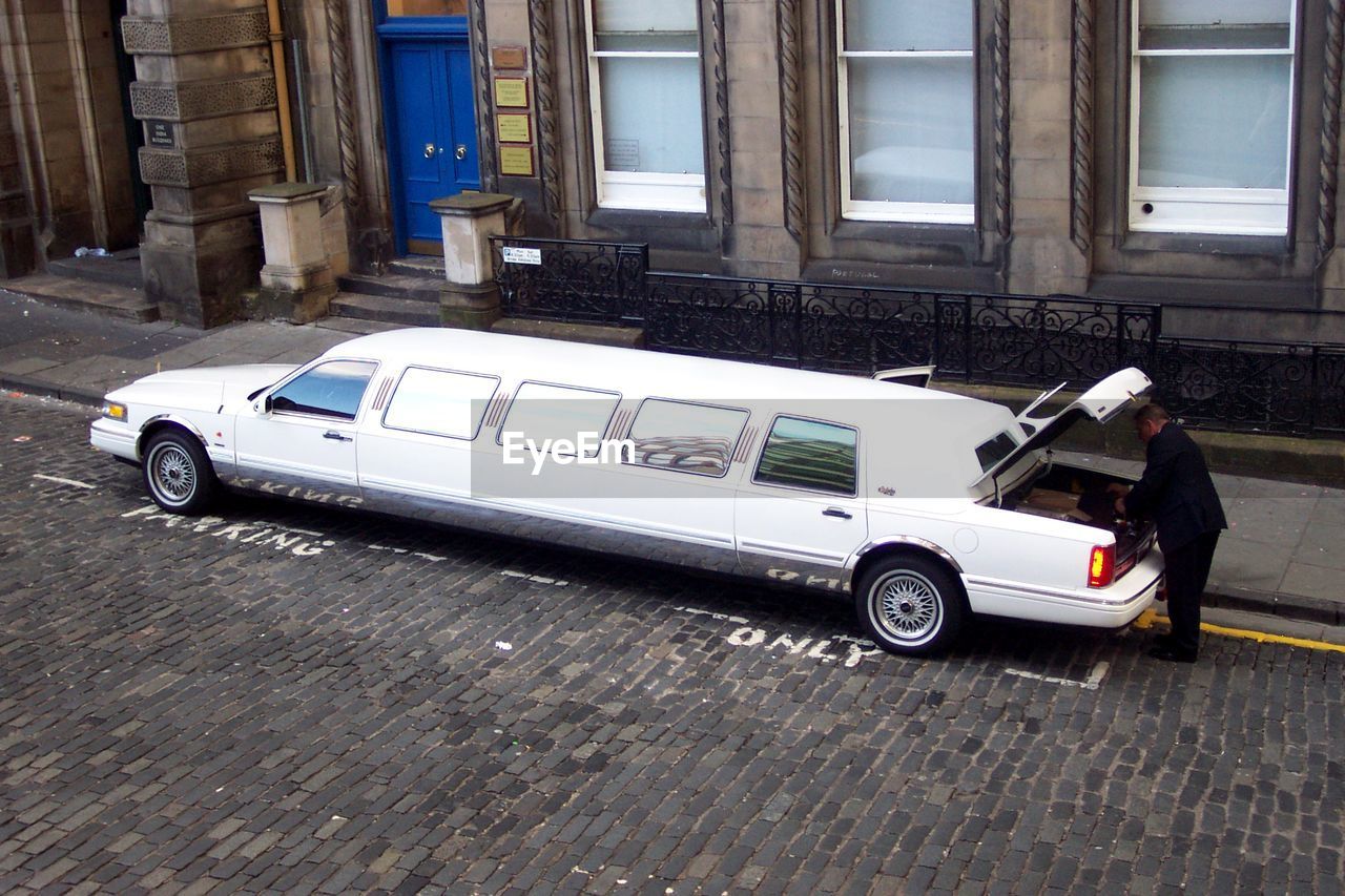 High angle view of driver at trunk of limousine