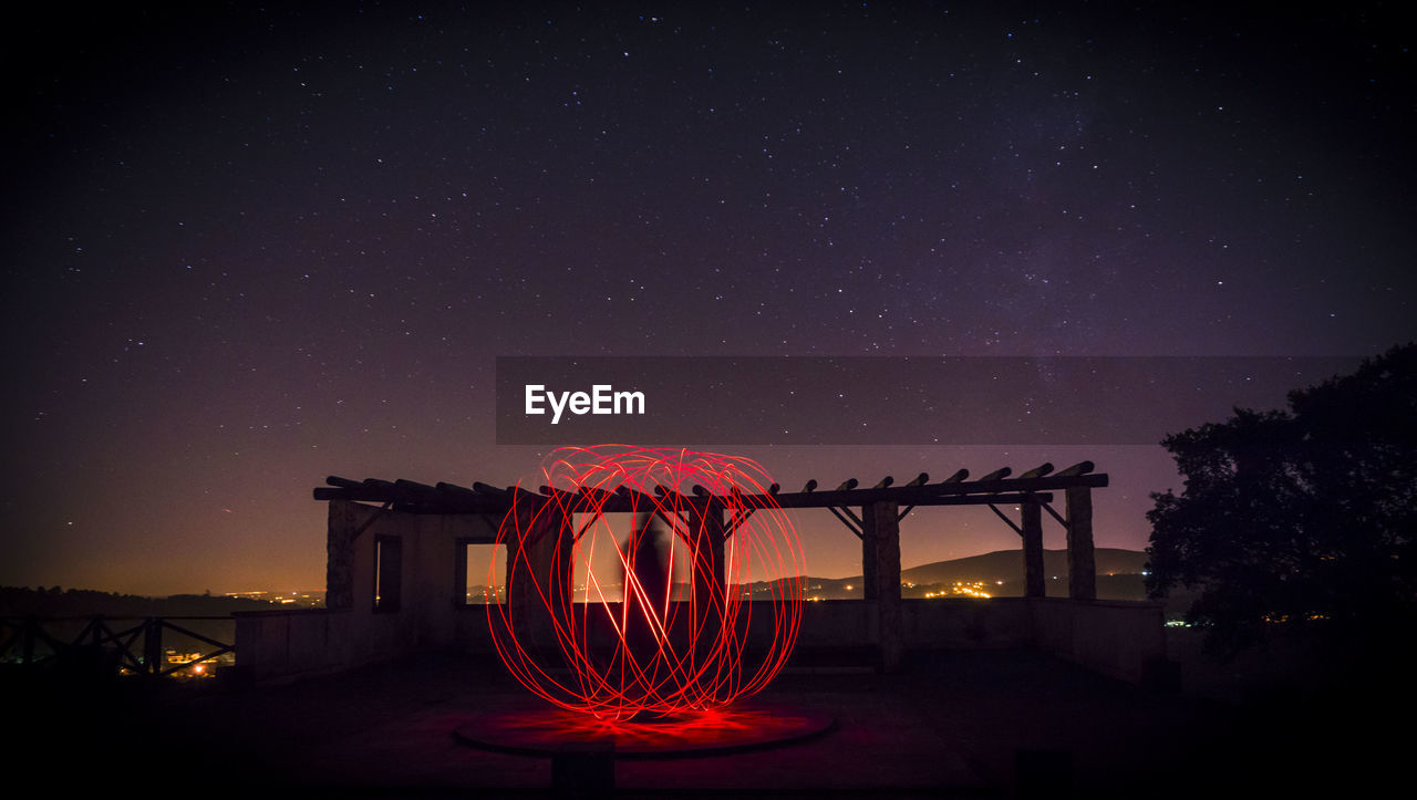 VIEW OF ILLUMINATED BUILT STRUCTURE AGAINST SKY AT NIGHT