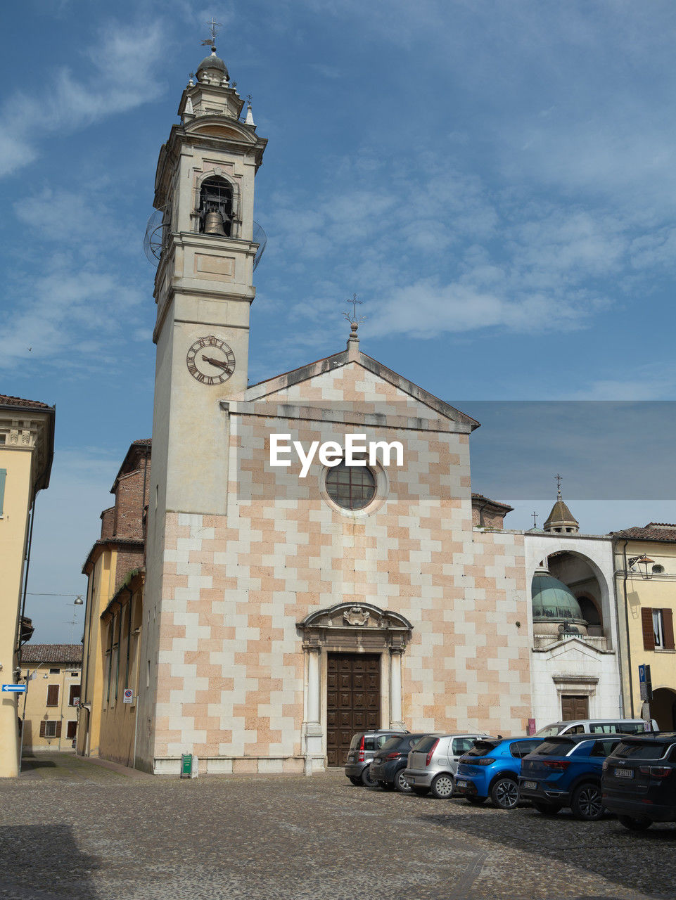 architecture, building exterior, built structure, place of worship, religion, building, tower, belief, spirituality, sky, town, travel destinations, clock tower, city, transportation, nature, clock, catholicism, mode of transportation, vehicle, time, day, history, street, bell tower, blue, cloud, the past, motor vehicle, travel, car, no people, landmark, outdoors, old