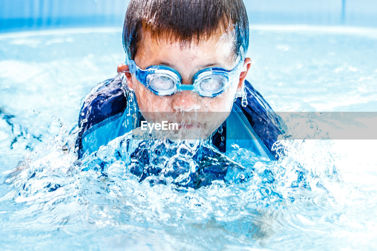 Boy splashing water in swimming pool