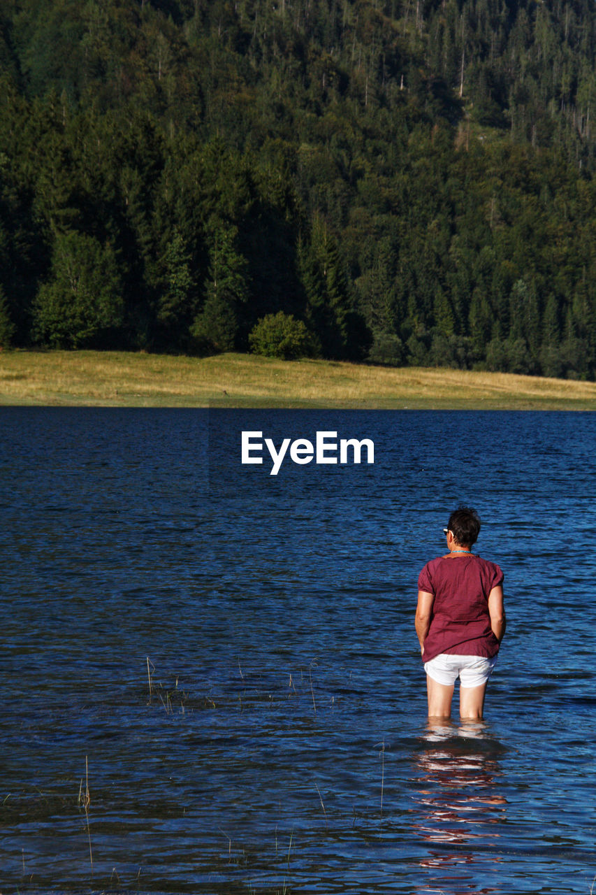 Rear view of woman standing in lake