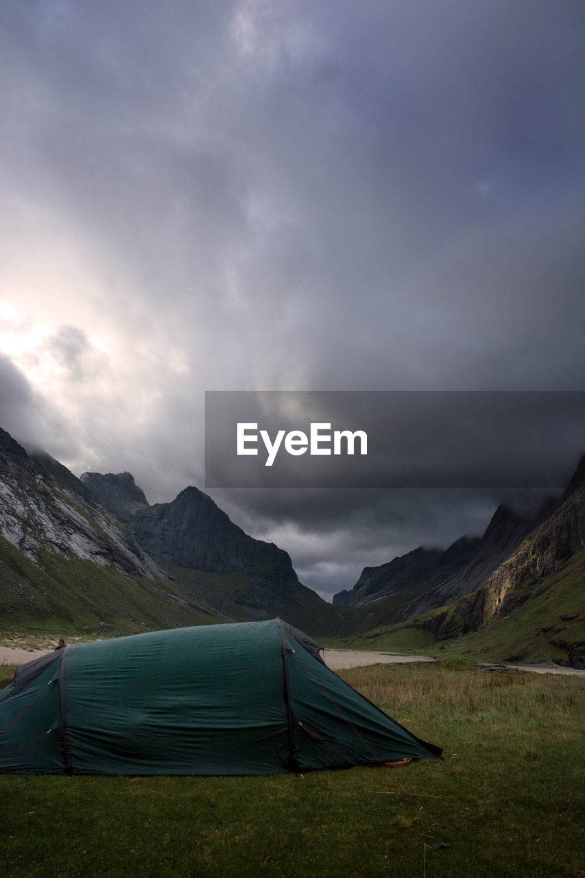 Tent on grass by mountains against sky