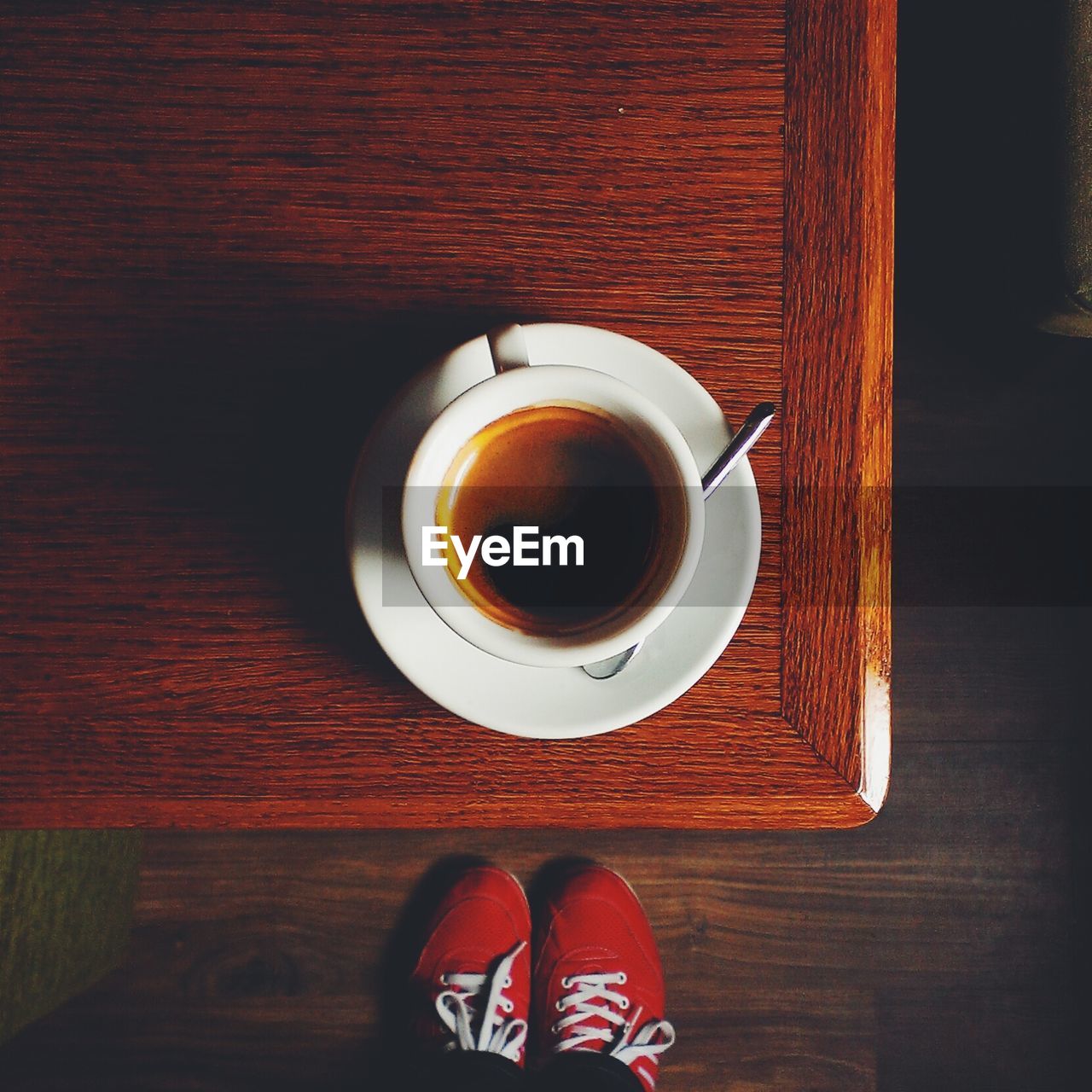 Directly above shot of coffee cup on table by person