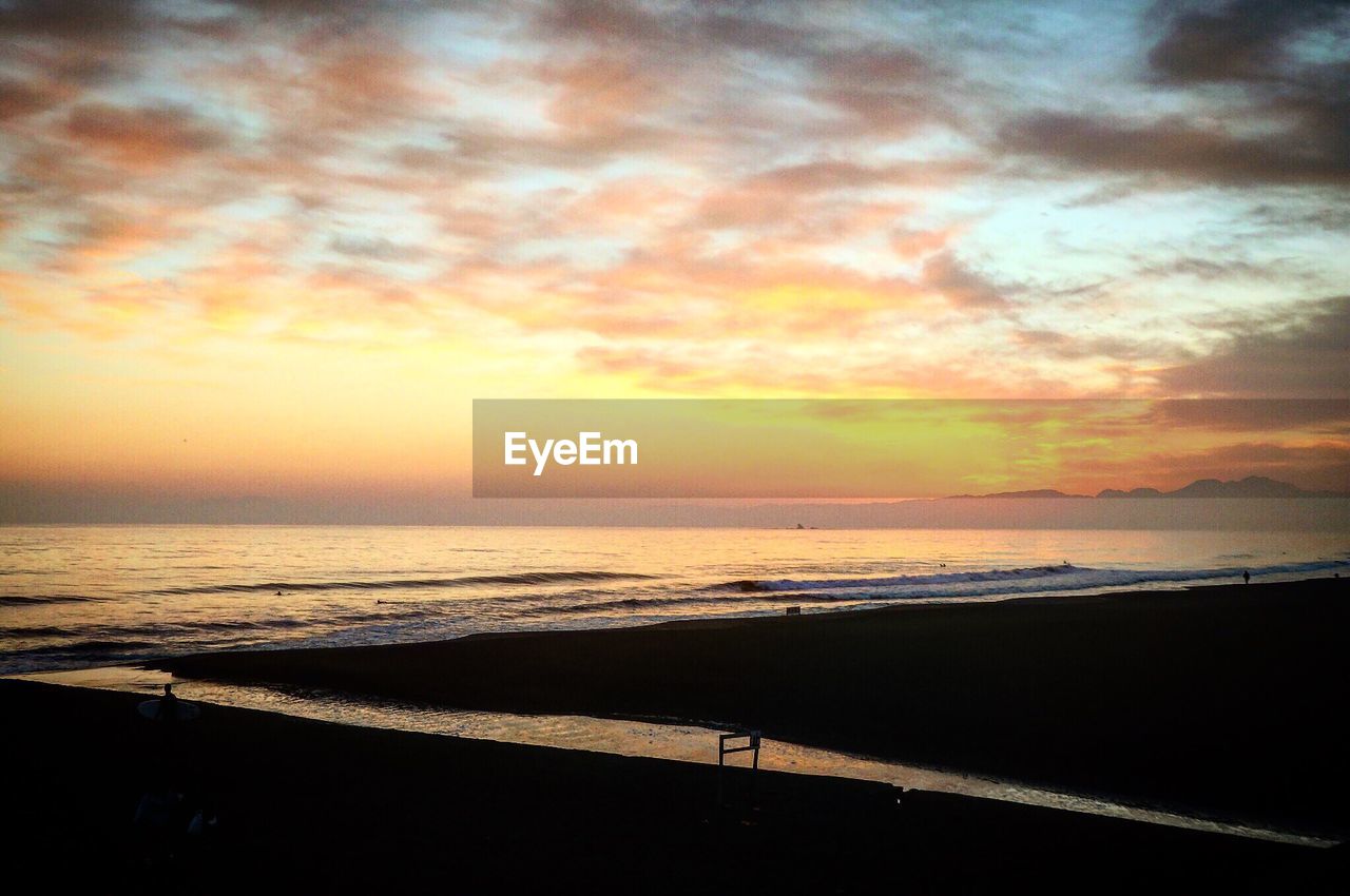 SCENIC VIEW OF BEACH AGAINST DRAMATIC SKY