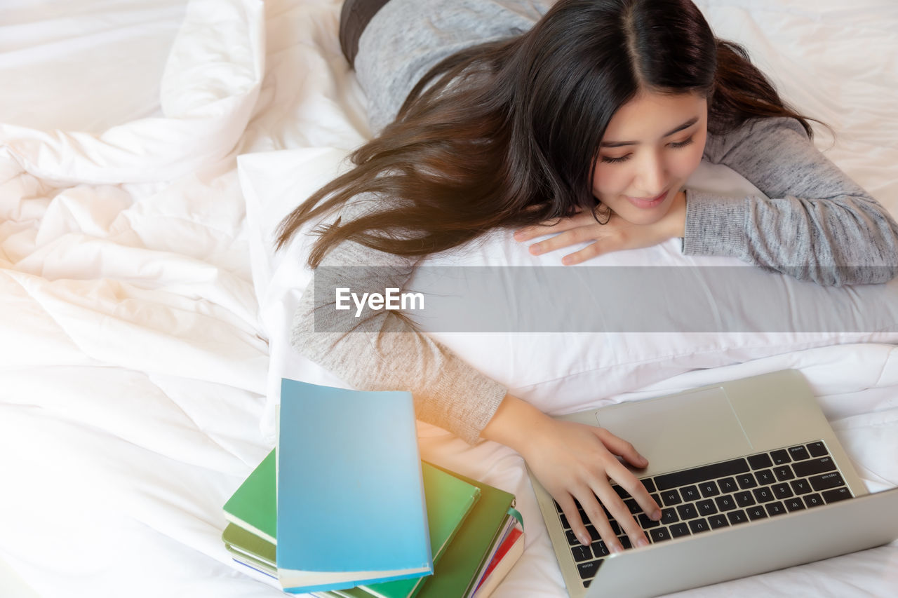 Woman using laptop on bed