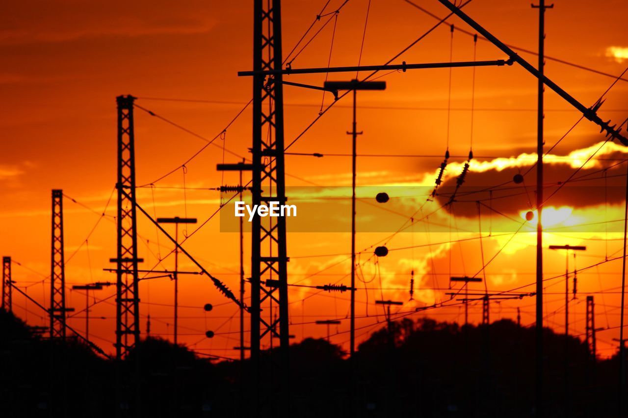 Low angle view of silhouette electricity pylon against sky during sunset