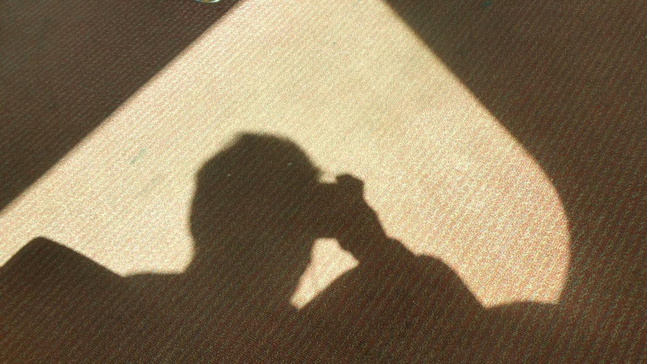 Shadow of photographer holding camera on carpet