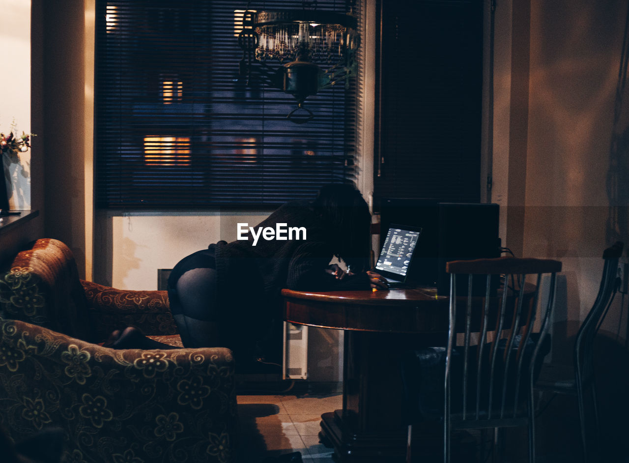 MAN SITTING ON SOFA IN ILLUMINATED ROOM