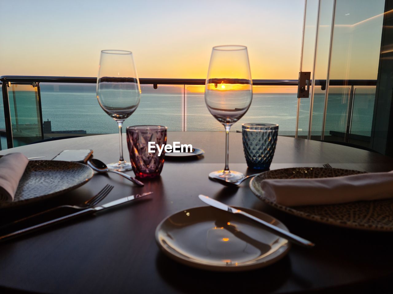 High angle view of champagne glasses on table against sea during sunset