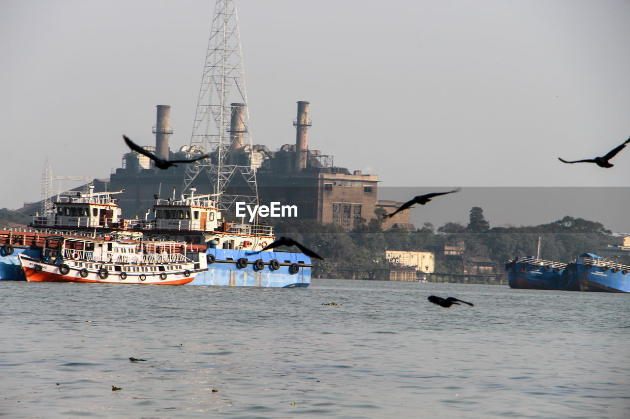 Moored boats in river against built structures