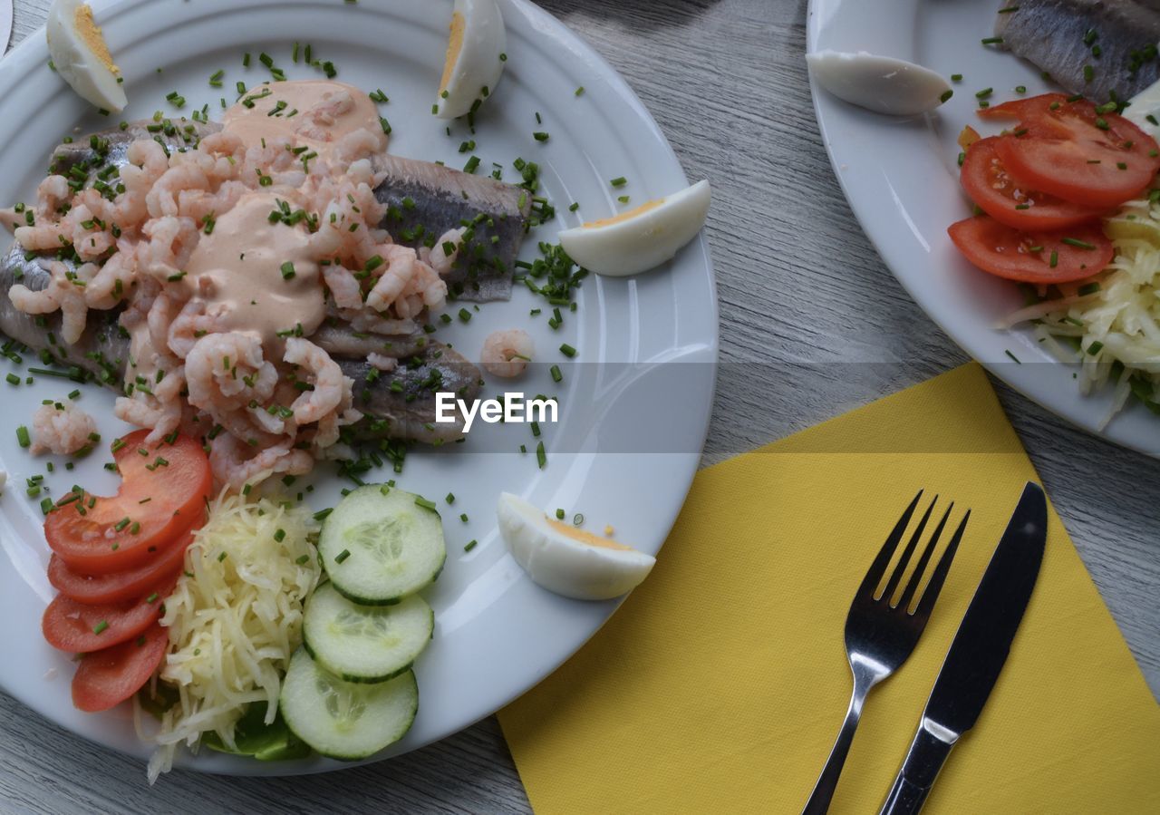 Close-up of seafood with sliced cucumber and tomato and egg served in plate