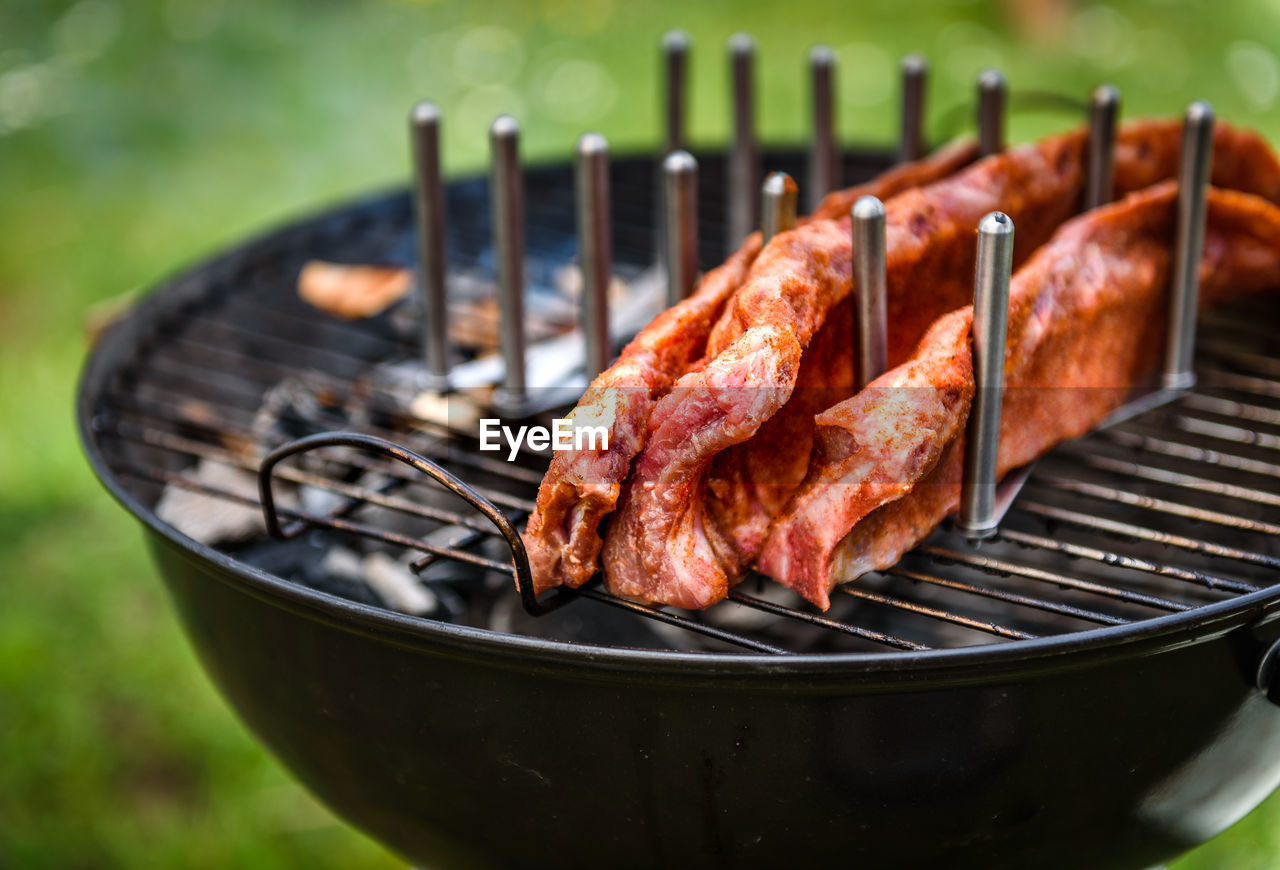 CLOSE-UP OF MEAT COOKING ON BARBECUE GRILL IN YARD