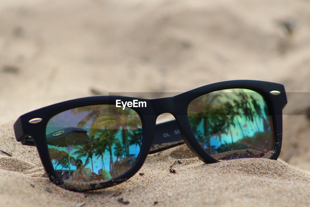 Close-up of sunglasses on sand