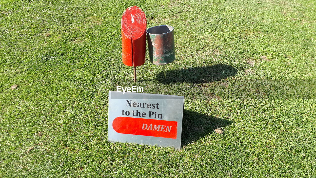 HIGH ANGLE VIEW OF WARNING SIGN ON GRASS