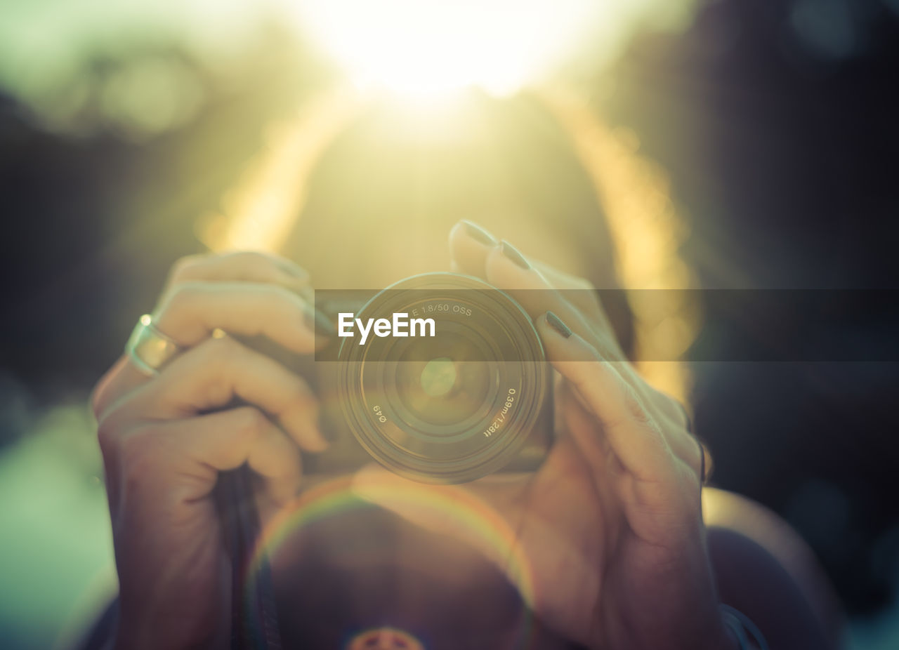 Close-up of woman holding camera on sunny day