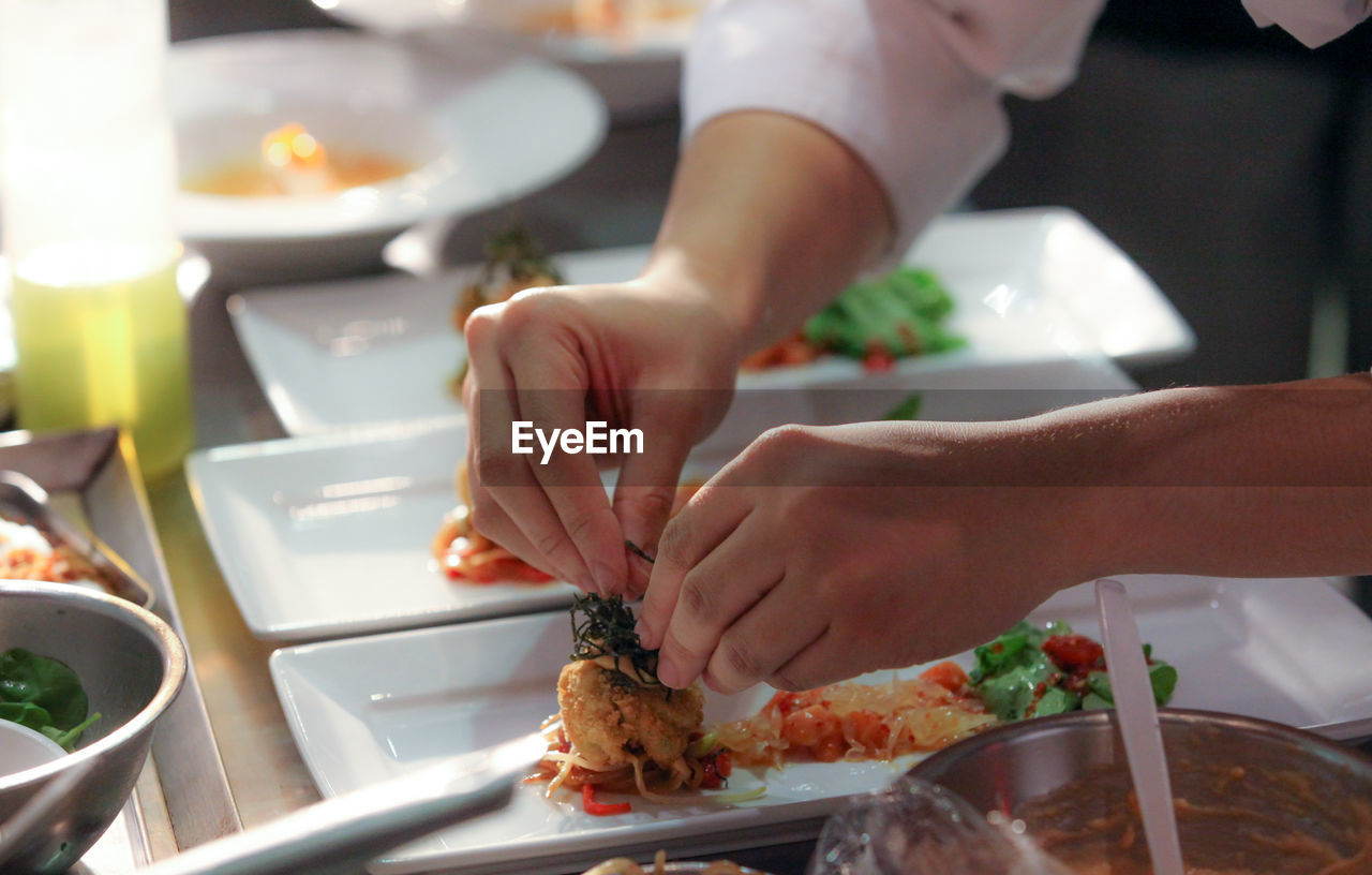 Cropped image of chef styling food in plate