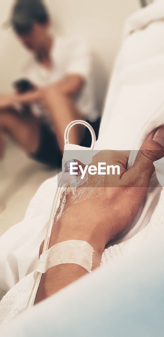 Cropped hand of patient on bed in hospital