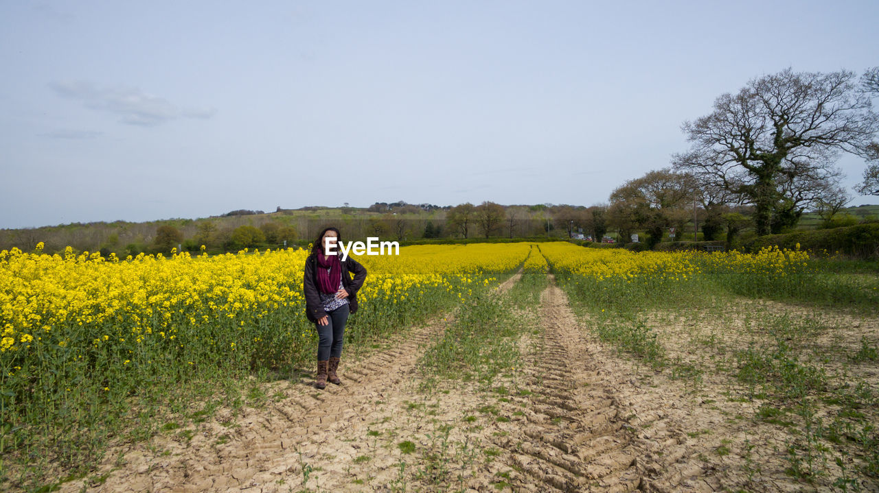 Full length of woman standing on oilseed rape field against sky