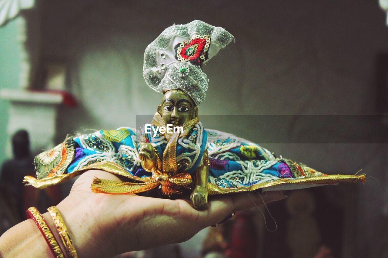 Cropped hand of woman holding statue at home