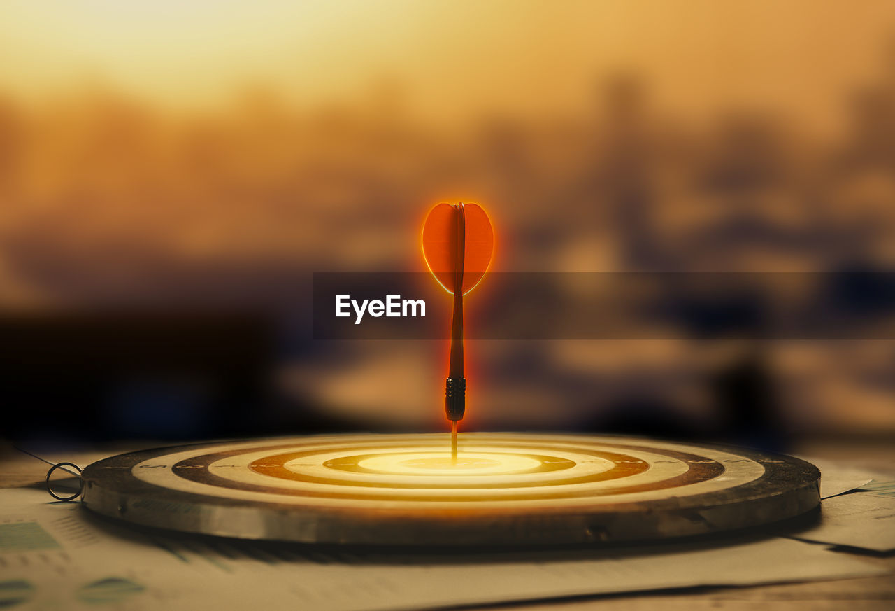 CLOSE-UP OF LIT CANDLE AGAINST SUNSET SKY