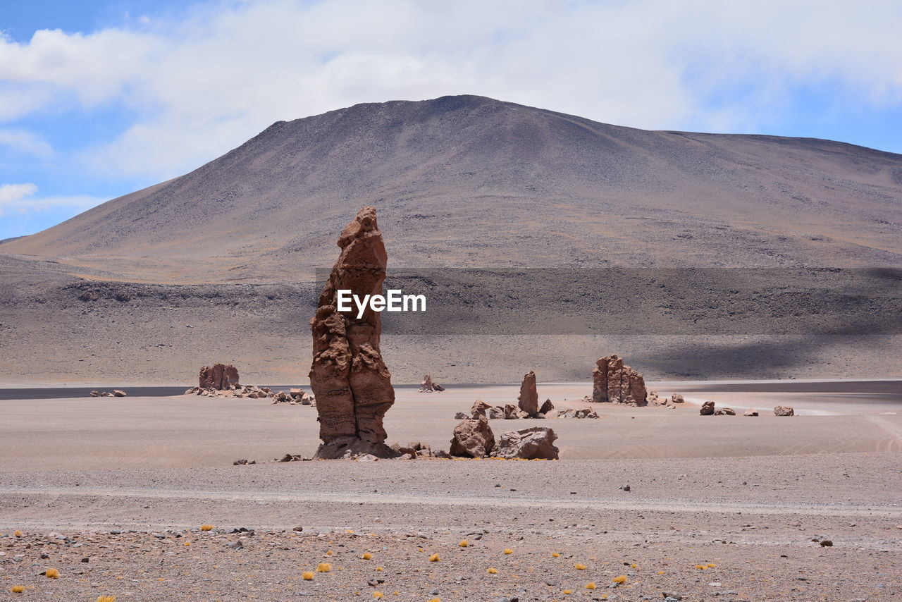 Scenic view of desert against cloudy sky