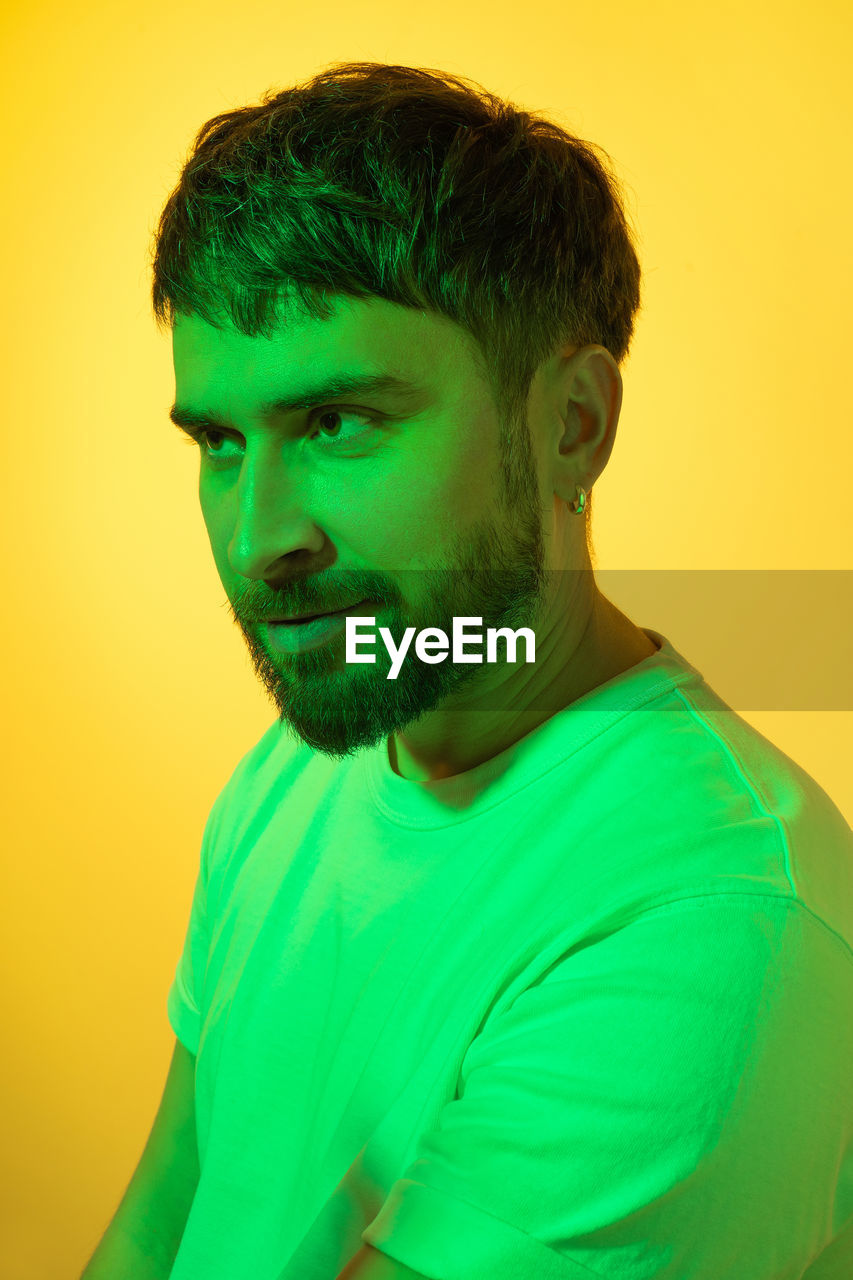 portrait of man looking away against yellow background