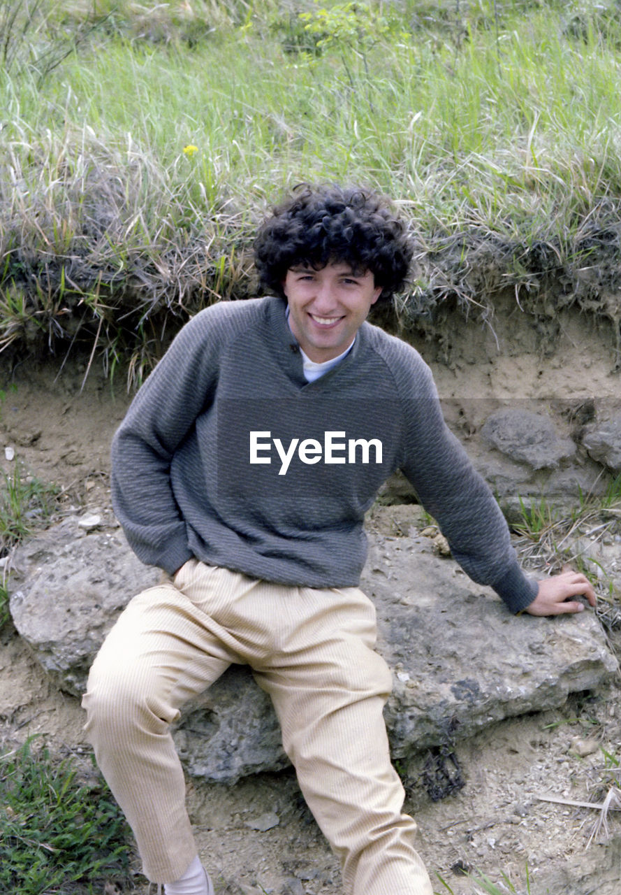 Side view of young man sitting on field