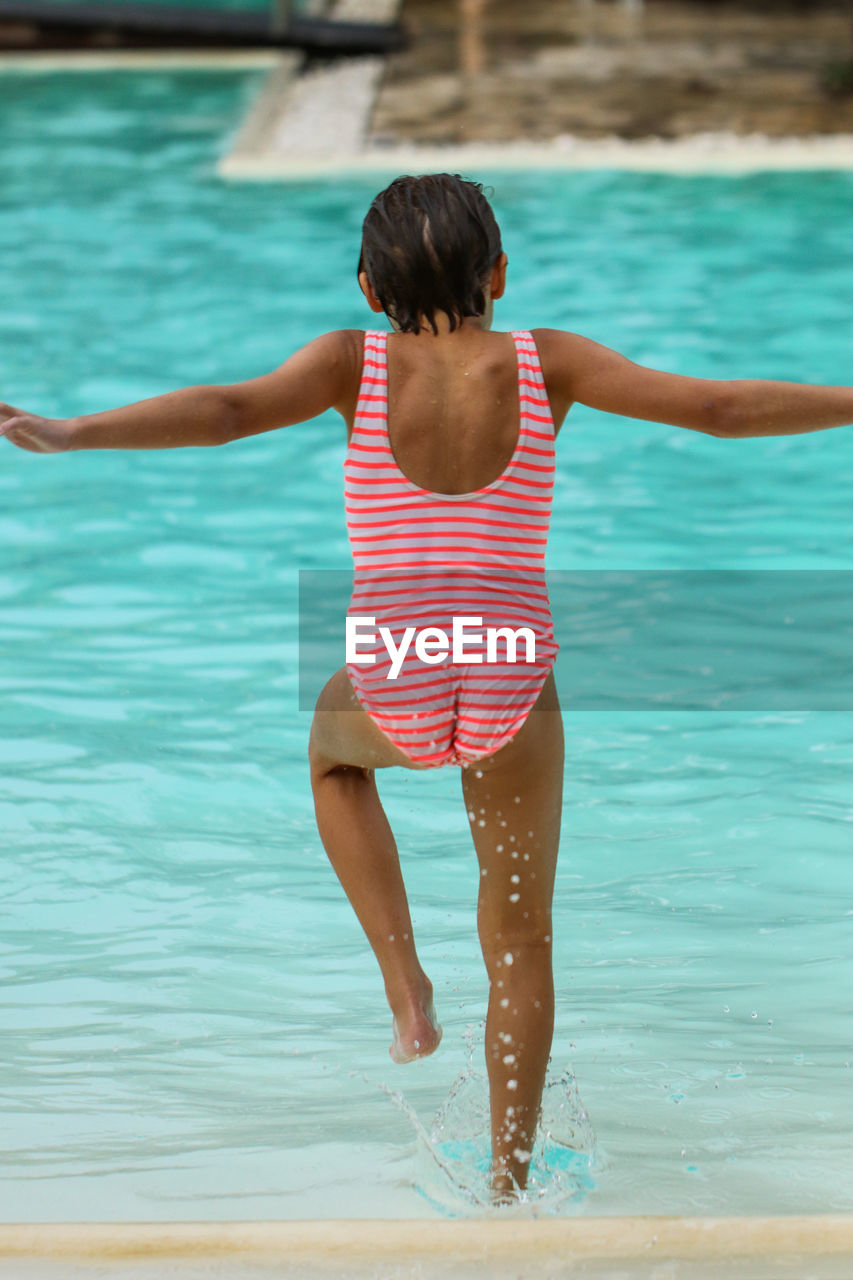 Rear view of girl running in swimming pool