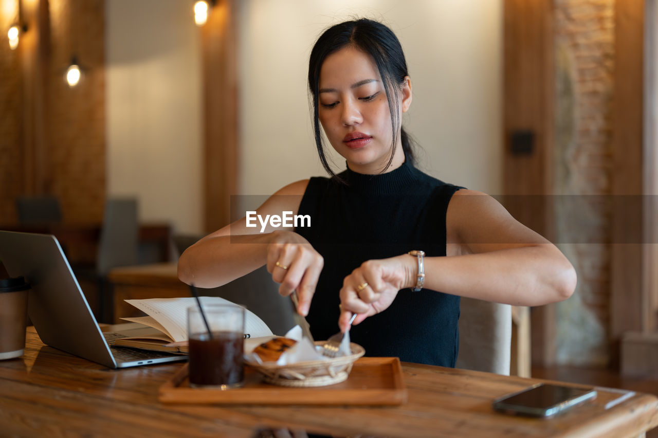 portrait of young woman using mobile phone at table