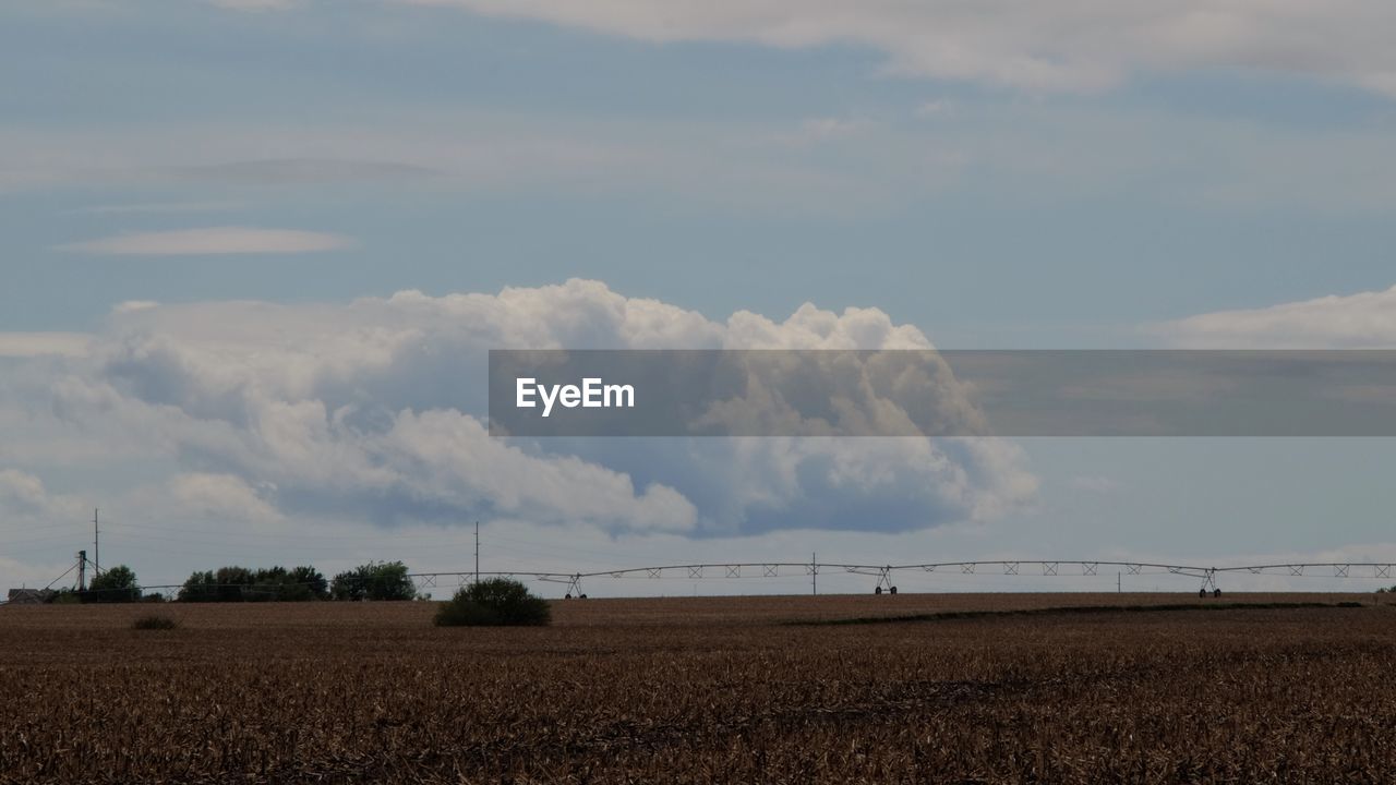 Scenic view of farm against cloudy sky