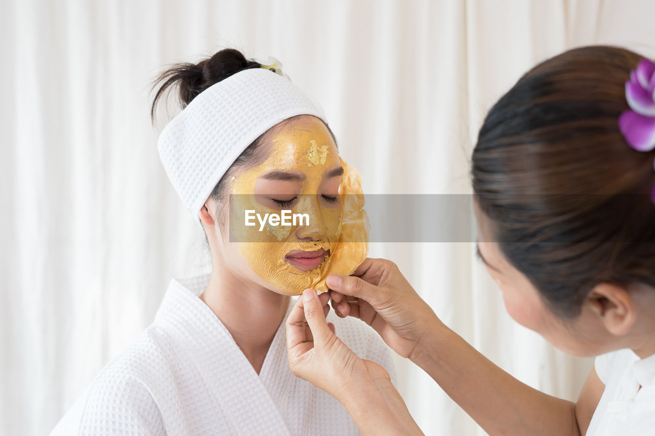 Massage therapist removing facial mask from young woman face