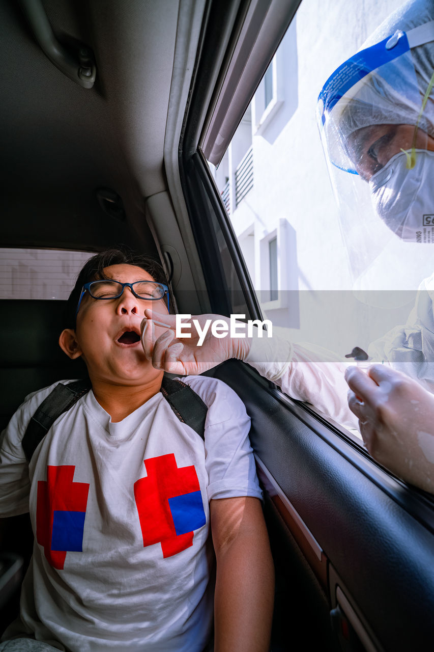 A young boy is taking a pcr swab test by drive thru lab.