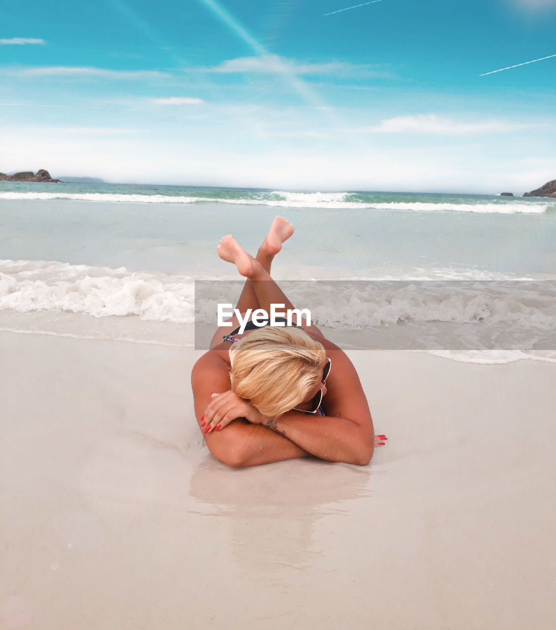 WOMAN RELAXING ON BEACH AGAINST SEA