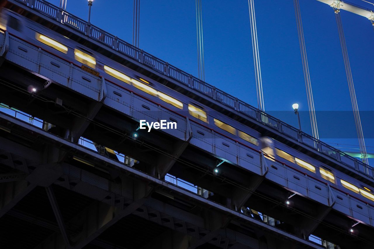 Low angle view of train on bridge against sky at dusk