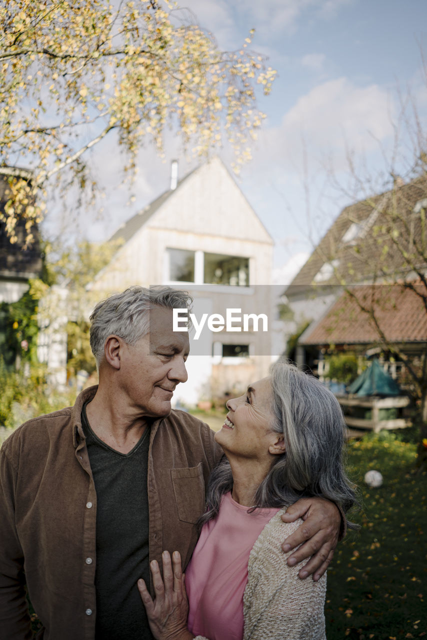 Happy senior couple in garden of their home in autumn