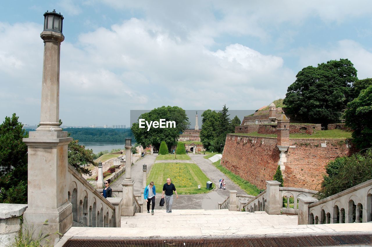 PEOPLE WALKING ON STEPS OF HISTORICAL BUILDING AGAINST SKY