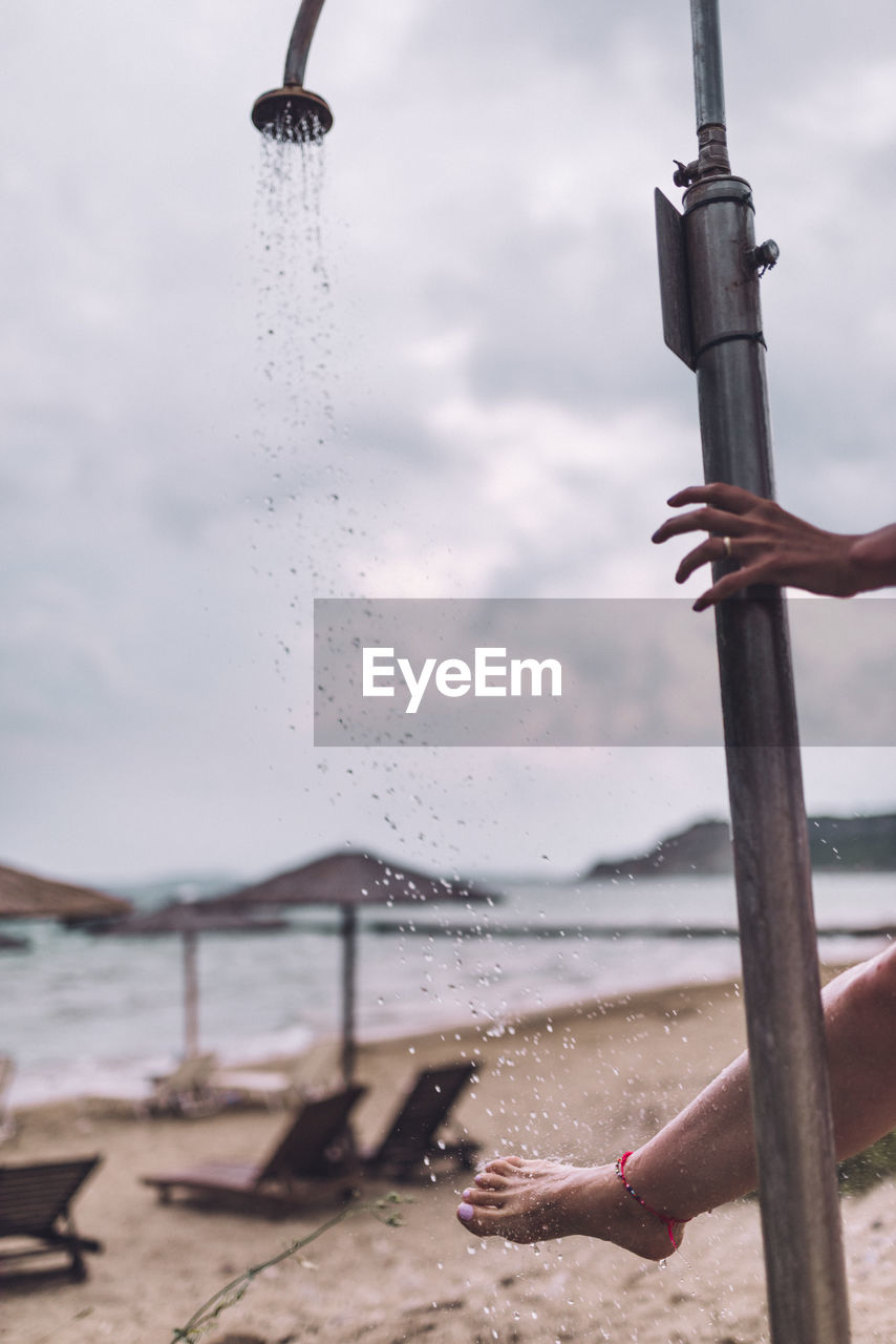 Cropped image of woman by shower at beach