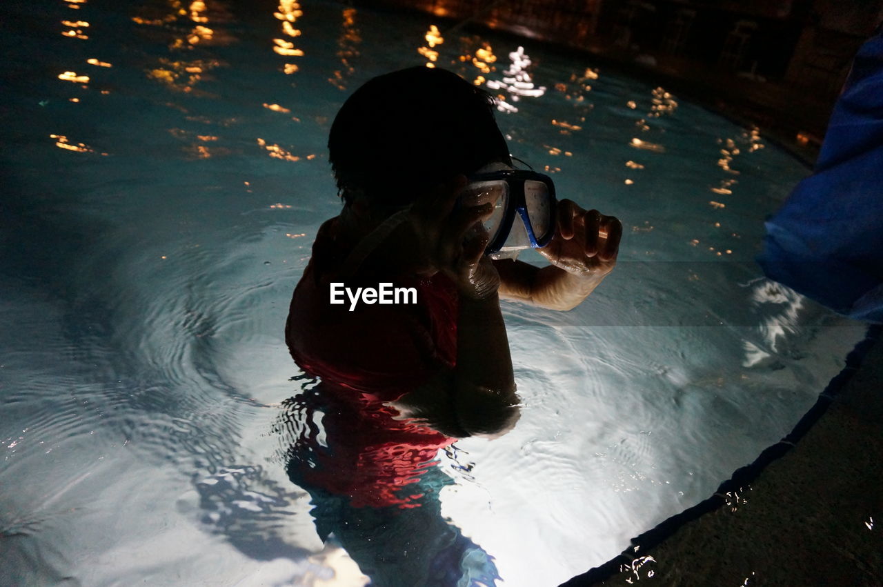 REFLECTION OF WOMAN PHOTOGRAPHING IN SWIMMING POOL