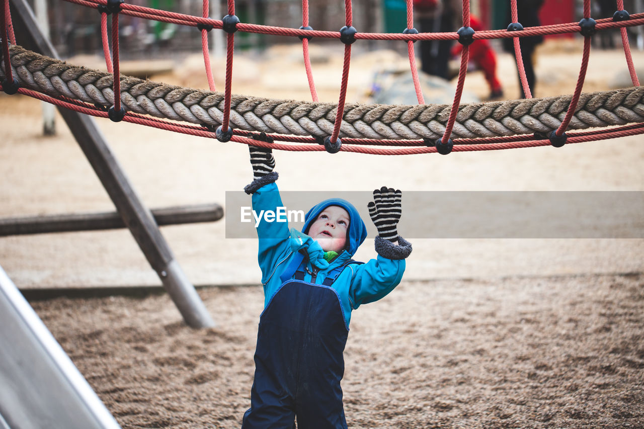 Full length portrait of boy standing on slide at playground