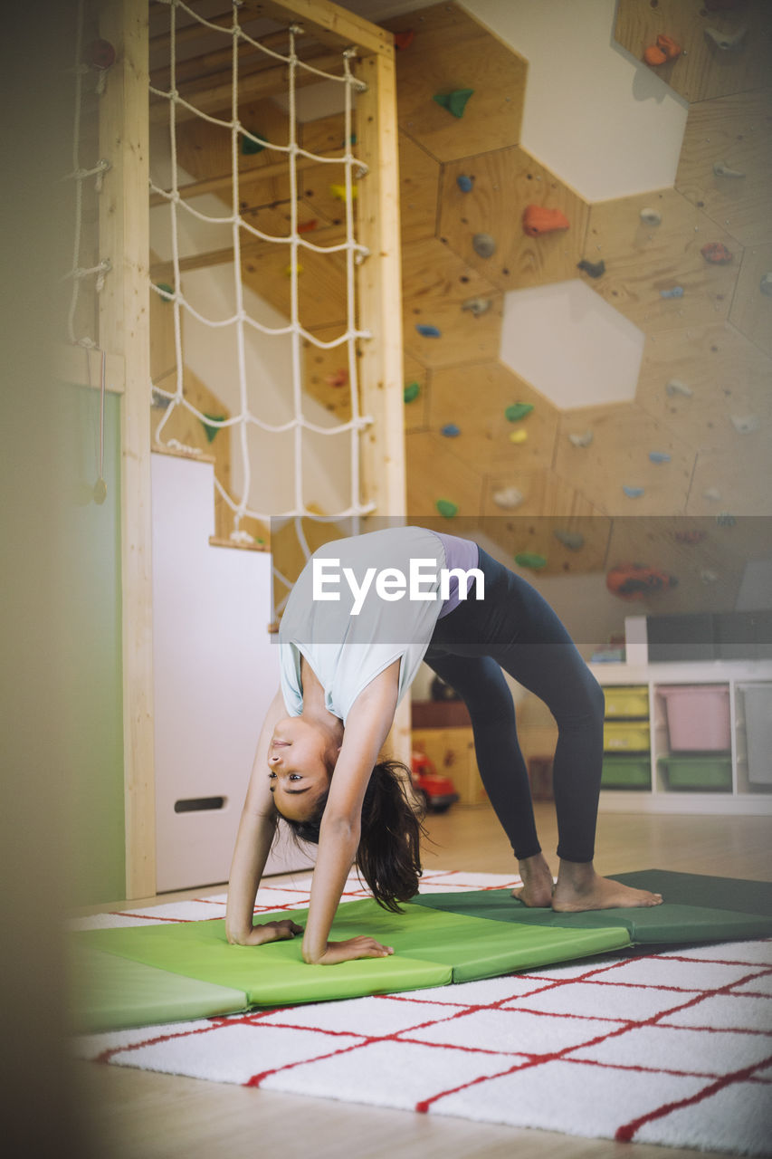 Sports girl practicing yoga in living room