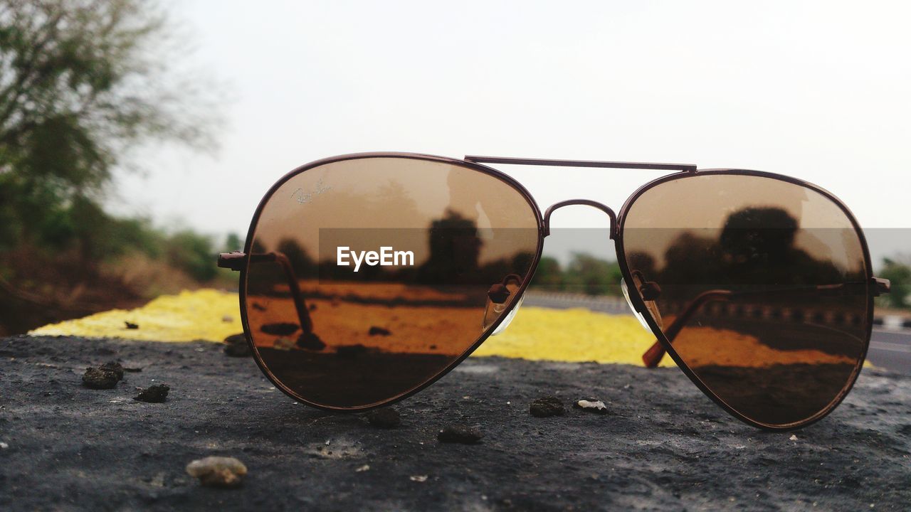 Close-up of sunglasses by road against sky