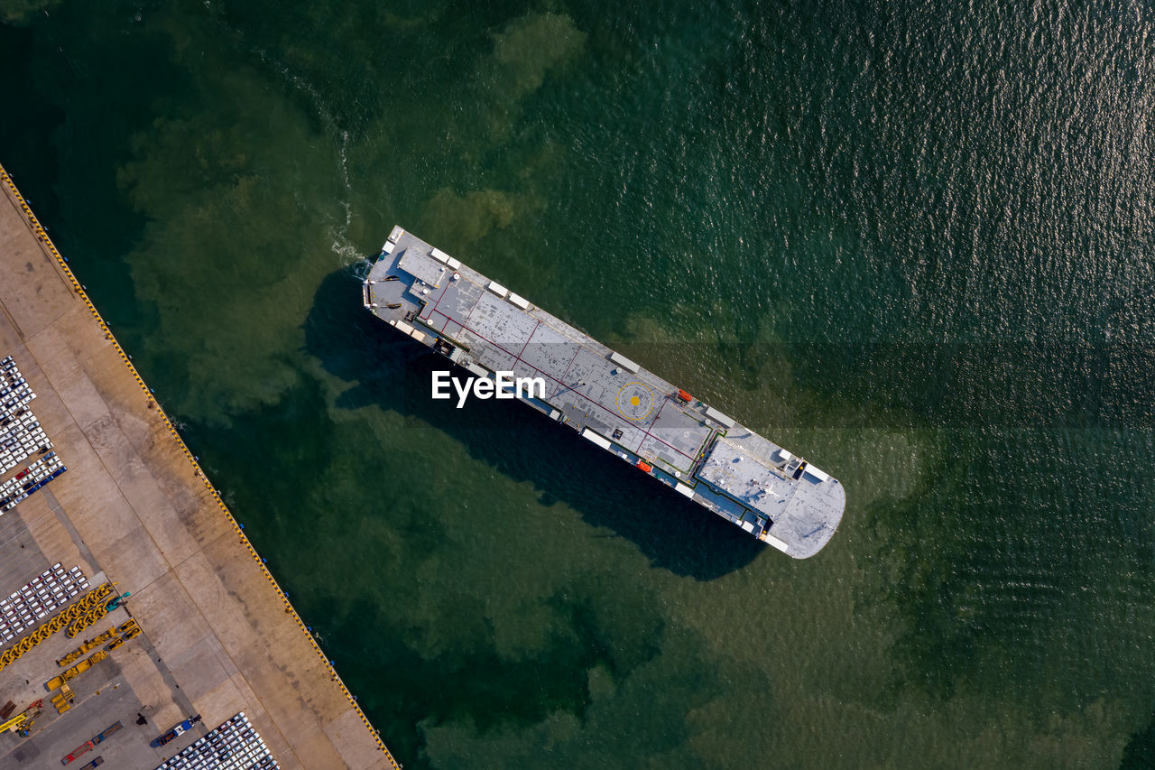 Aerial view of roro vehicle carrier vessel parking for loading car at sea port.