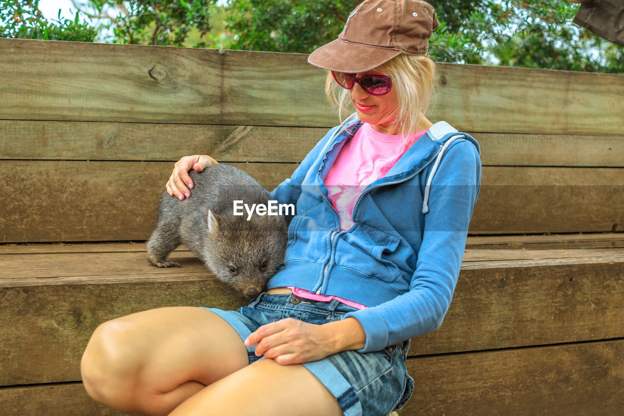 Woman sitting with wombat at bench